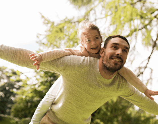 Father carrying his daughter on his back and playing outside