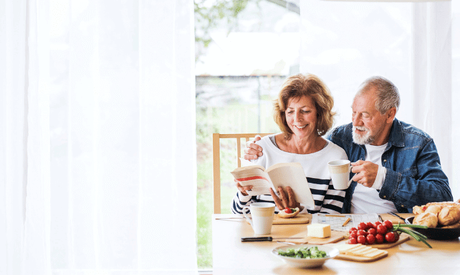 Affectionate older couple reading together at breakfast