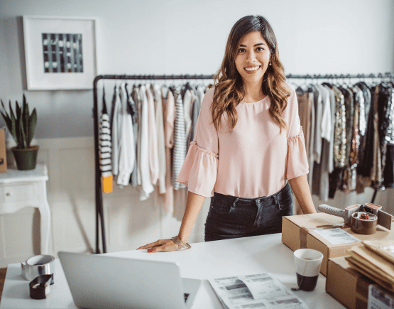 Smiling young business owner taking inventory at her clothing shop