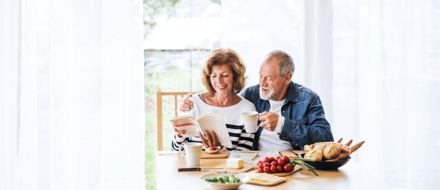 Affectionate older couple reading together at breakfast