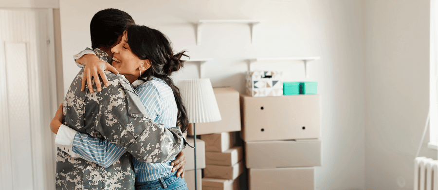 Young US Army soldier hugging his partner in a new home